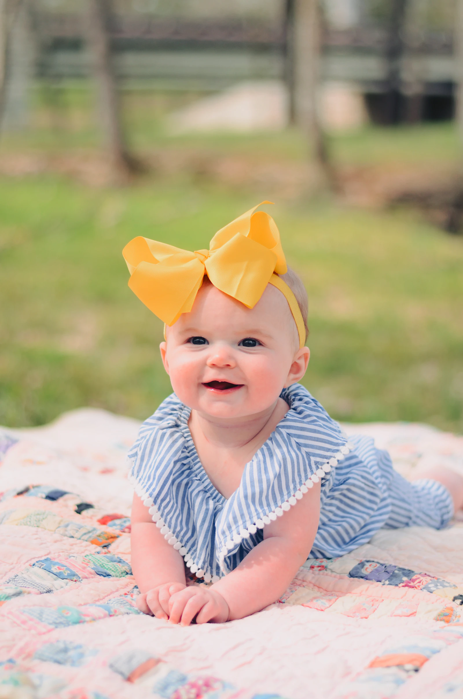 Smiling baby doing tummy time on a quilt outdoors